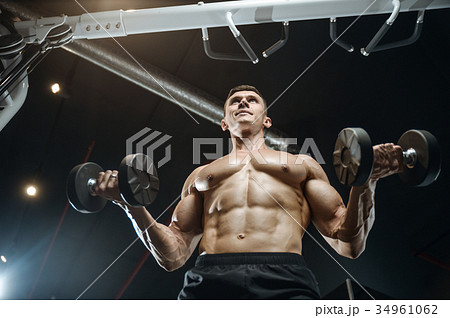 Handsome model young man training arms in gym Handsome model young man training arms in gym 34961062