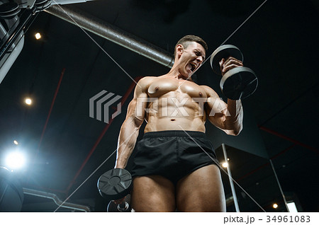Handsome model young man training arms in gym 34961083