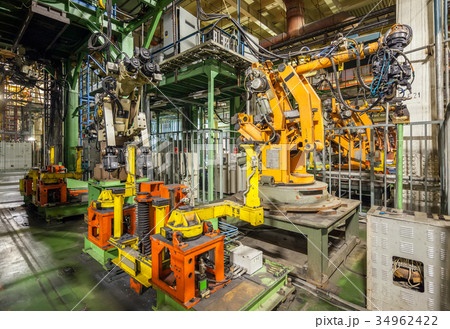 Yellow robots welding cars in a production line. 34962422