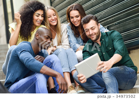 Multi-ethnic group of young people looking at a tablet computer 34973502