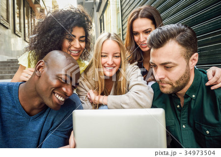 Multi-ethnic group of young people looking at a tablet computer 34973504
