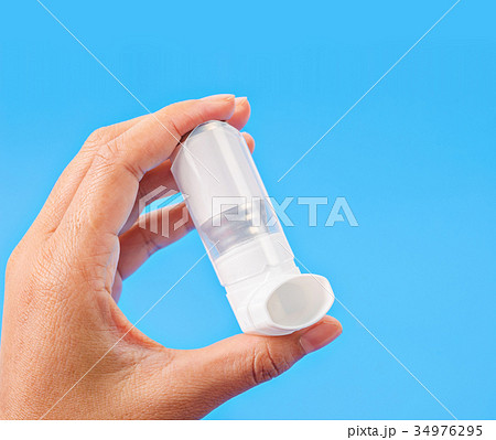 Person holding a white asthma inhaler. 34976295