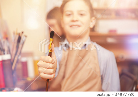 Positive boy showing painting brush into camera Positive boy showing painting brush into camera 34977730