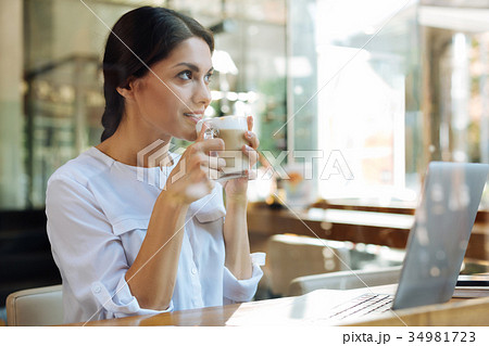 Charming dark-haired woman drinking latte in cafe Charming dark-haired woman drinking latte in cafe 34981723