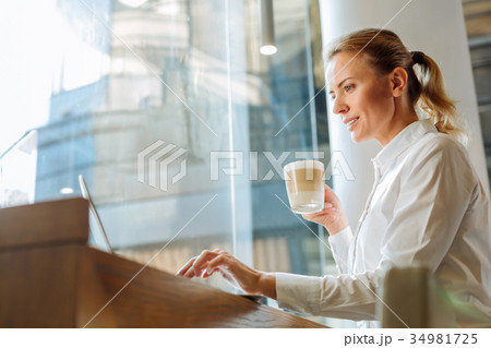 Inspired woman drinking latte and browsing web in 34981725