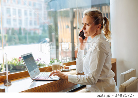 Young businesswoman talking on the phone in cafe Young businesswoman talking on the phone in cafe 34981727