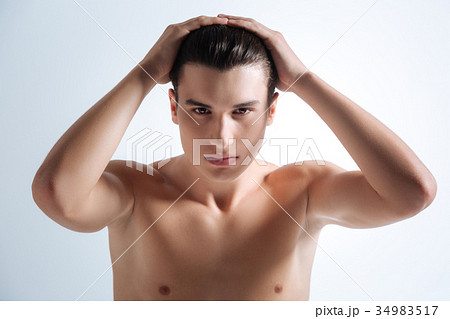 Handsome brunette smoothing his hair Handsome brunette smoothing his hair 34983517