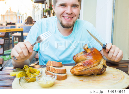 man eating knuckle of pork and drinks beer 34984645