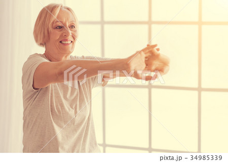 Cheerful aged woman doing stretching exercises 34985339