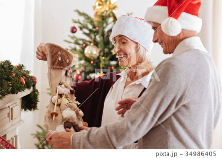 Happy couple staring at Christmas stocking Happy couple staring at Christmas stocking 34986405