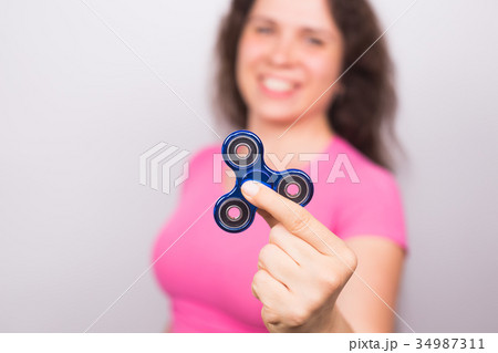 young woman playing with a fidget spinner, focus 34987311