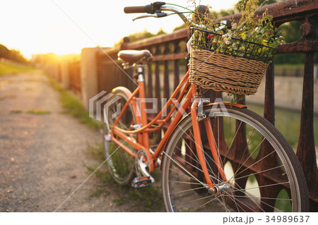 Beautiful bicycle with flowers in a basket stands on the street Beautiful bicycle with flowers in a basket stands on the street 34989637