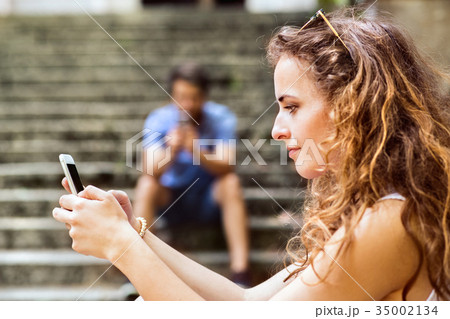 Young couple with smartphones sitting on stairs in 35002134