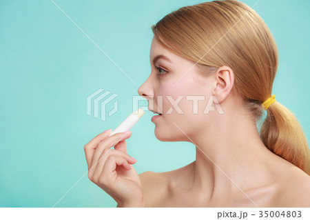 woman applying balsam for lips 35004803