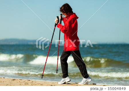 Nordic walking. Woman hiking on the beach. 35004849