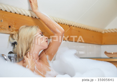 beautiful young blonde woman taking a relaxing bath with foam beautiful young blonde woman taking a relaxing bath with foam 35005641