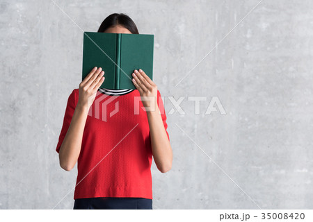 Charming young woman is covering behind storybook 35008420