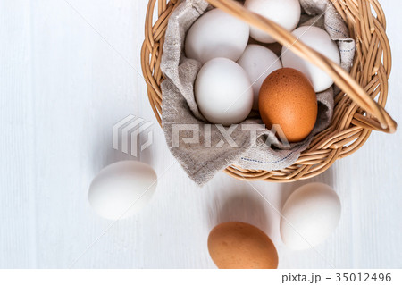 Basket with white and brown natural eggs on white Basket with white and brown natural eggs on white 35012496