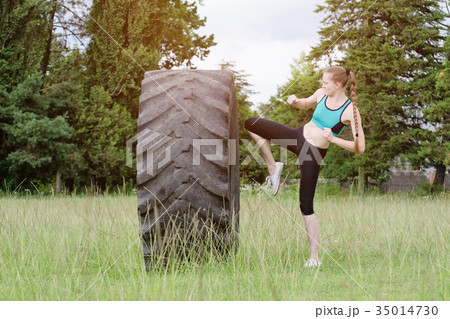 Girl in sports clothes is hitting tire her knee 35014730