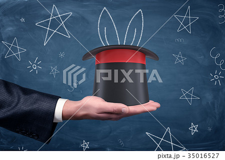 A businessman's palm with a magician's hat resting A businessman's palm with a magician's hat resting 35016527