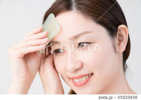 セルフマッサージをする女性 かっさ 顔の写真素材