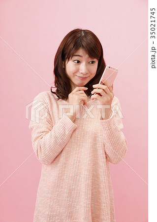 スマホを持つ女性 ピンクバック スマホを持つ女性 ピンクバック 35021745