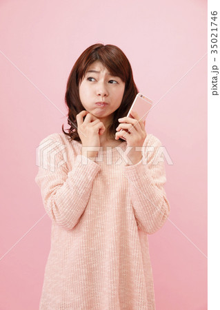 スマホを持つ女性　ピンクバック 35021746