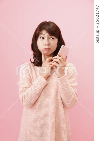 スマホを持つ女性 ピンクバック スマホを持つ女性 ピンクバック 35021747