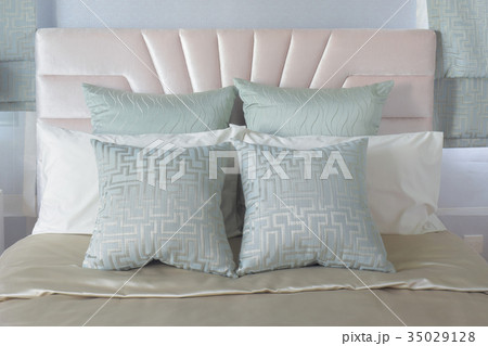 Pastel pillows setting on bed with satin bedding 35029128