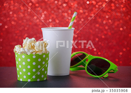 popcorn, drink and glasses for movie on red bokeh 35035908