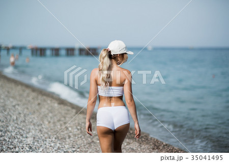 Back view of fitness girl walking along the beach Back view of fitness girl walking along the beach 35041495