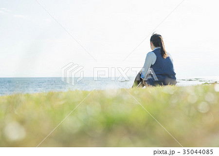 女子高生 海 草原 座るの写真素材