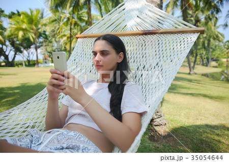 Relaxed young woman looking at mobile phone Relaxed young woman looking at mobile phone 35054644