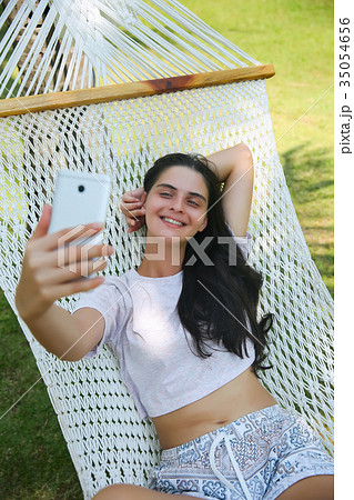 Relaxed young woman looking at mobile phone Relaxed young woman looking at mobile phone 35054656