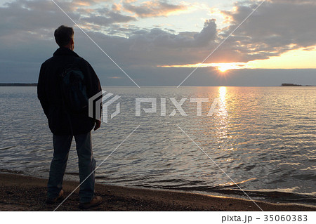 Man standing on the river bank at sunset 35060383