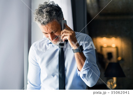 Mature businessman with smartphone in a hotel room Mature businessman with smartphone in a hotel room 35062041