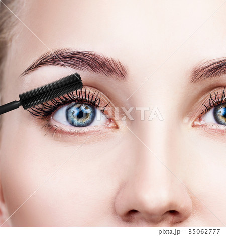 Woman applying mascara on eyelashes with brush. 35062777