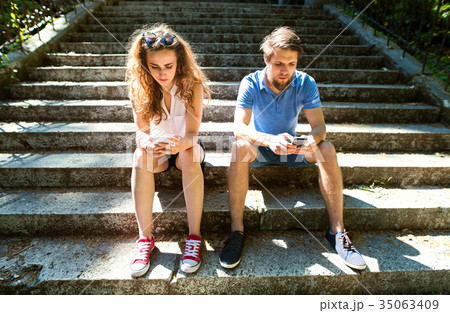 Young couple with smartphones sitting on stairs in 35063409