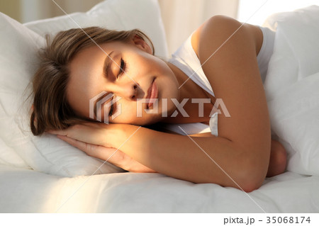 Beautiful young woman sleeping while lying in bed Beautiful young woman sleeping while lying in bed 35068174