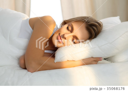 Beautiful young woman sleeping while lying in bed Beautiful young woman sleeping while lying in bed 35068176