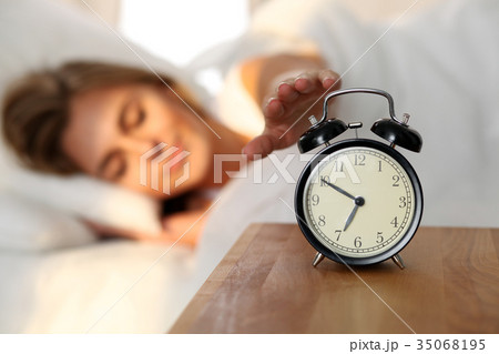 Sleepy young woman stretching hand to ringing 35068195