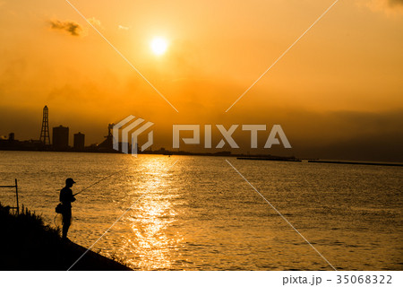 シルエットの釣り人 港の夕焼け サンセット 夕日の中で 釣り の写真素材