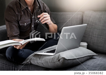 Handsome Young Man Sitting on the Living Room Couch, Casual youn Handsome Young Man Sitting on the Living Room Couch, Casual youn 35068382