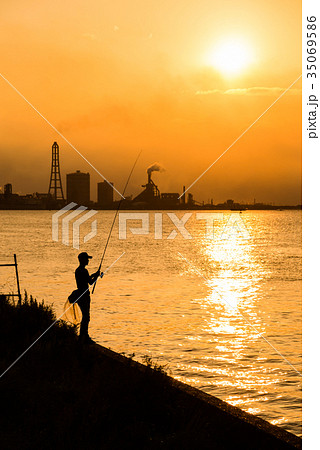 夕日 夕方 夕焼け 海 釣り人 シルエット 海岸線 逆光 海岸線の写真素材