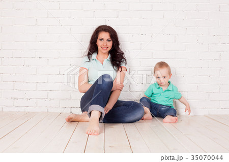 mom and young boy son sit on the floor brick wall 35070044
