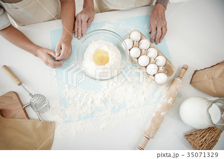 Skillful senior woman teaching girl to bake Skillful senior woman teaching girl to bake 35071329