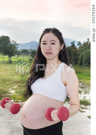 Sporty pregnant woman exercising with dumbbells. 35079164