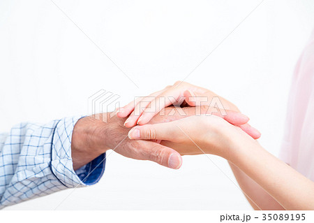 若い看護師とおじいちゃん 手を握る 手に触れる 老人ホーム デイケアセンター 車椅子 の写真素材