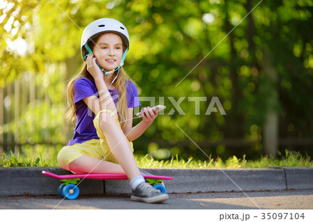 Pretty little girl learning to skateboard on beautiful summer day in a park Pretty little girl learning to skateboard on beautiful summer day in a park 35097104