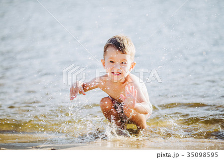 boy child playing makes splashes, beats hands on the water  35098595